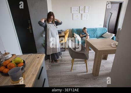 Mature mother setting the table while child learning and using pc tablet gadget at home Stock Photo