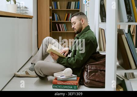 Adult Hispanic Man Studying in Library for Migrant Education Stock Photo