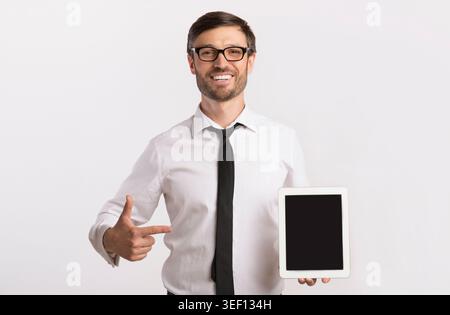 Businessman Holding Tablet Pointing Finger At Blank Screen, Studio Shot Stock Photo