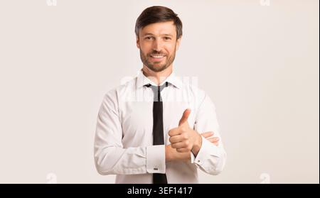 Businessman Gesturing Thumbs Up Smiling At Camera, Isolated, Studio Shot Stock Photo