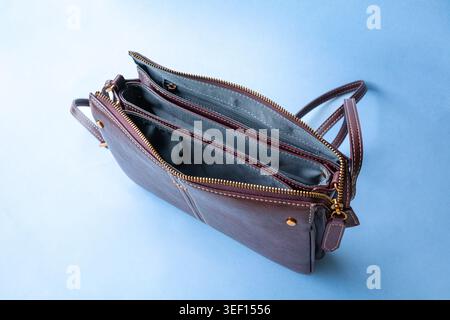 Open women handbag showing inner compartment. Isolated on light blue background. Stock Photo