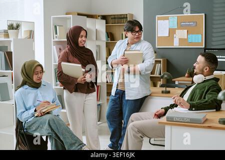 Multiethnic College Students Discussing Books in Language Class Stock Photo