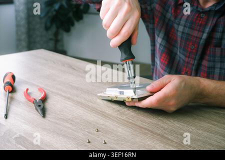 Male engineer repairman disassembles computer hard drive with a screwdriver. Concept of repairing, service, electronics and technology of computer. Stock Photo