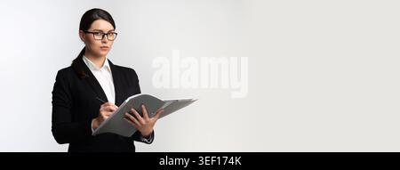 Professional Woman in Business Attire Holding a Clipboard and Taking Notes in a Modern Setting Stock Photo