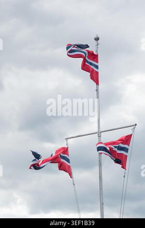 Three norwegian pennant flags fluttering on a mast under a grey sky, symbolizing national identity, patriotism, and scandinavia Stock Photo