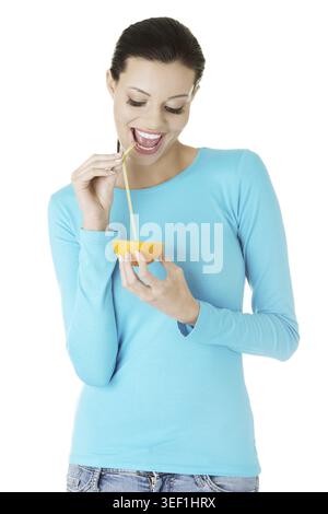 Attractive smiling young woman drinking orange juice straight from fruit Stock Photo