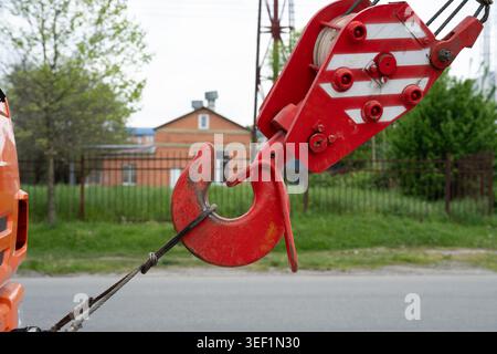 Industrial lifting equipment and steel cable block used for heavy machinery operations. Close-up of a heavy duty red crane hook and wire rope at a con Stock Photo