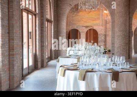Tables set with glasses and place settings in a luxurious event venue with brick arches Stock Photo
