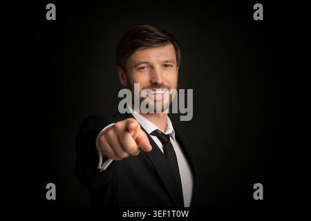 Businessman Pointing Finger Smiling At Camera, Studio Shot Stock Photo