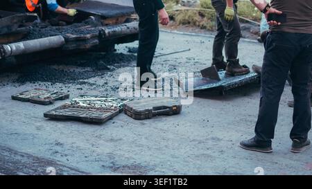 Road workers using heavy machinery and tools to lay fresh asphalt. Stock Photo