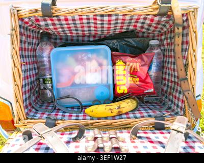 Wicker picnic hamper with checkered lining packed with snacks and water bottles at a classic car show in the United Kingdom Stock Photo