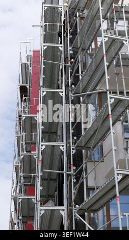 Scaffolding structure covering a residential building facade, providing access for construction workers during renovation and maintenance work against Stock Photo