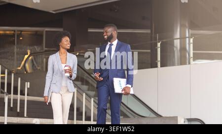 Two african american employees leaving office building for coffee break Stock Photo