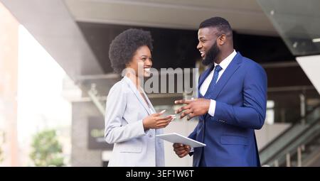 Two coworkers with digital tablet, discussing new project outdoors Stock Photo