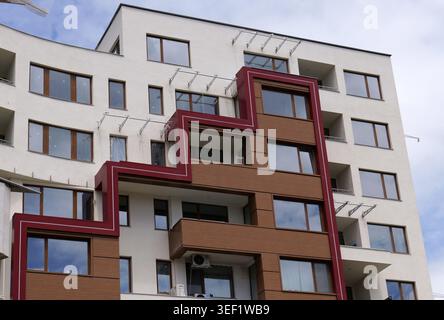 Modern apartment building with white facade, brown panels and a bold geometric red motif, showcasing contemporary urban design, clean lines and vibran Stock Photo