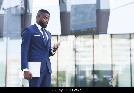 African American Businessman Using Mobile Phone During Walk In City Stock Photo