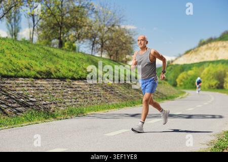 Full length shot of a fit elderly man jogging outdoors on a sunny morning Stock Photo
