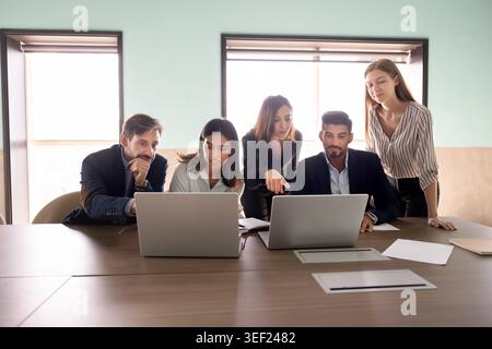 Focused diverse businesspeople collaborating on task using laptops Stock Photo