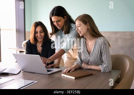 Group of multiethnic women colleagues collaborating on laptop in office Stock Photo