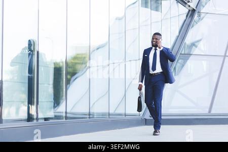 Entrepreneur Talking On Cellphone On The Way To Work Indoors Stock Photo