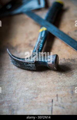 Weathered hammer and steel ruler on wooden workbench with copy space set in a workshop Stock Photo