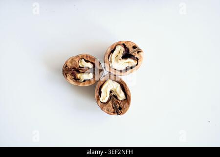 Cracked walnut halves with whole nuts on white background. Stock Photo