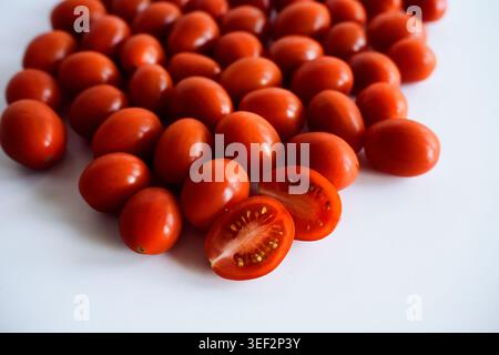 Ripe red cherry tomatoes on white background, one cut in half. Stock Photo