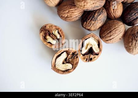 Cracked walnut halves with whole nuts on white background. Stock Photo