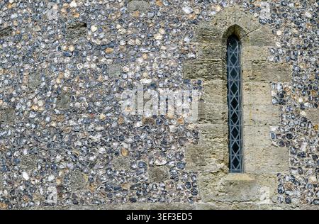 Historic narrow lancet window with stone quoins set in a knapped flint wall. Medieval castle architecture, England, UK. Stock Photo