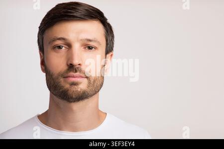 Young Man With Beard and Short Hair Poses Against a Plain Background Stock Photo