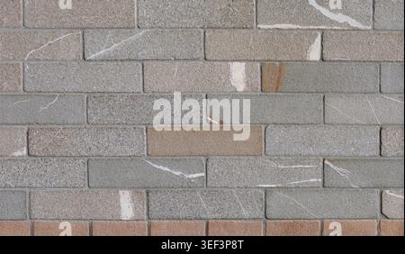 Stone wall made of granite tiles of different colors. Background and texture. Stock Photo