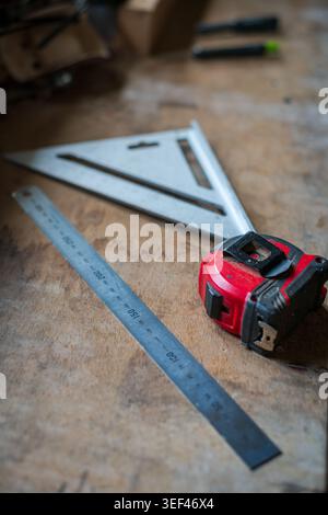 Speed Square, Steel ruler and tape measure measuring tools on wooden workbench in carpentry workshop Stock Photo