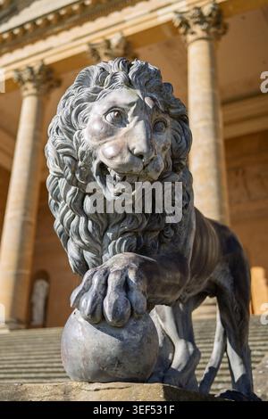 A majestic carved stone lion statue standing proudly on a high rectangular masonry plinth base at Stowe Gardens, Buckinghamshire, England Stock Photo
