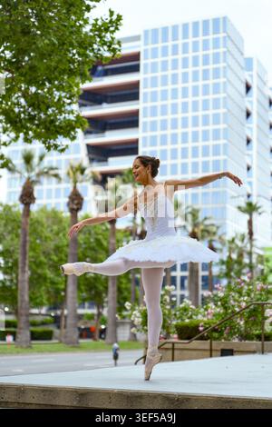 Ballerina performing pointe pose in modern city plaza Stock Photo