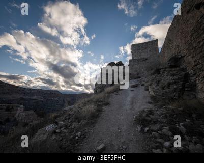 Ancient stone fortress walls and pathway winding up a hill under a cloudy skyraw Stock Photo