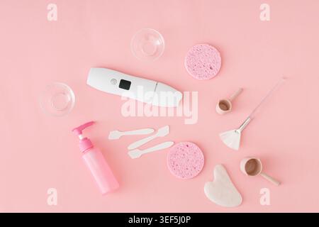 Trendy skincare composition with facial cleansing tools, beauty accessories and spa essentials on pastel pink background. Skincare and beauty concept. Stock Photo