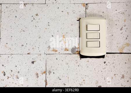 Minimalist light switch mounted on a textured white stone wall, featuring clean interior design aesthetics, architectural detail, and contemporary hom Stock Photo