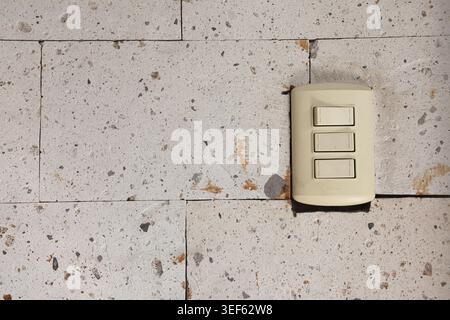 Minimalist light switch mounted on a textured white stone wall, featuring clean interior design aesthetics, architectural detail, and contemporary hom Stock Photo