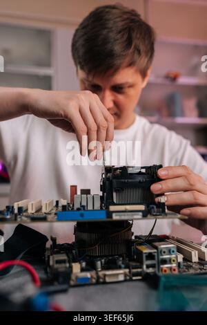 Person inspecting and repairing computer components, using screwdriver to adjust hardware on motherboard, concept of technology services and Stock Photo