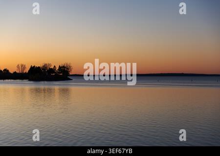 Sunset over calm river with tree silhouette. Ottawa River in the evening Stock Photo