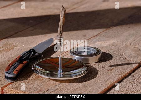 Survival set with knife, compass, and solar lighter on textured wooden background Stock Photo