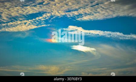 Rainbow Fragment and Wispy Clouds in Bright Blue Sky Nature Background Stock Photo