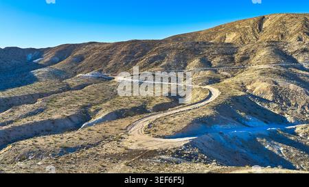 Aerial view of the winding road through lush green hills leading to the ...