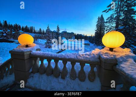 Winter Evening Lights and Snow Covered Luxury Hotel in Alberta Mountain Forest Stock Photo