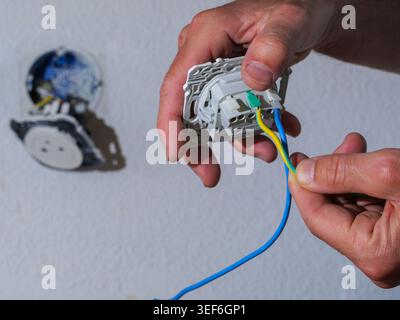 Close-up of connecting electrical wires to a new wall socket during home electrical installation work. Stock Photo
