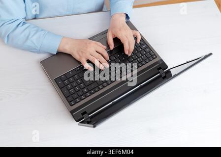 Overhead workspace scene with hands typing on laptop keyboard, designed for technology, programming and remote office productivity themes Stock Photo