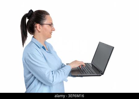 Side profile of smiling woman using laptop isolated on white background, illustrating remote work, online communication and digital productivity Stock Photo