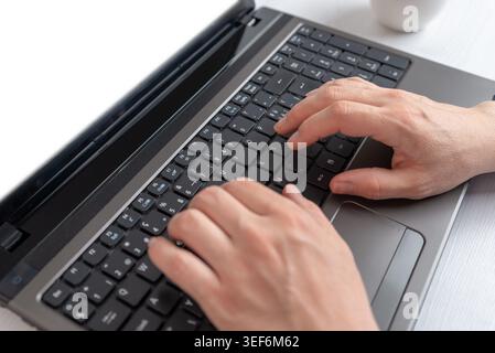 Closeup typing scene on laptop keyboard with clean white mockup area, designed for technology advertising, remote office and digital workspace concept Stock Photo