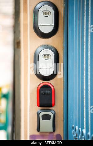 Various lock boxes with keys code inside located on wall near entrance gate at apartment building. Stock Photo