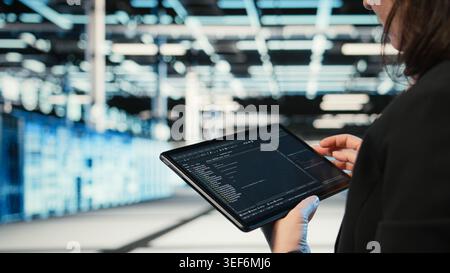 Using coding application, tablet and programmer in data center optimizing equipment rigs. Adjusting system parameters, programming script close up and IT professional in server hub camera A Stock Photo